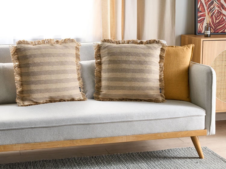 Dekoratives Sofa mit drei Kissen, zwei davon mit Streifenmuster und Fransen