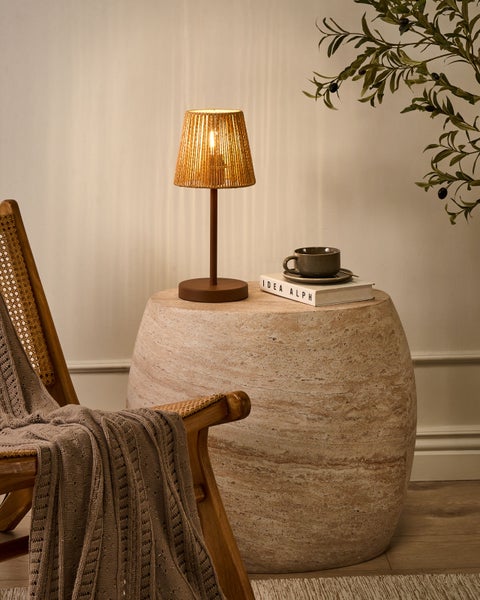 Gemütliche Szene mit einem Sessel, einer Tischlampe, einem Beistelltisch, einem Buch und einer Tasse