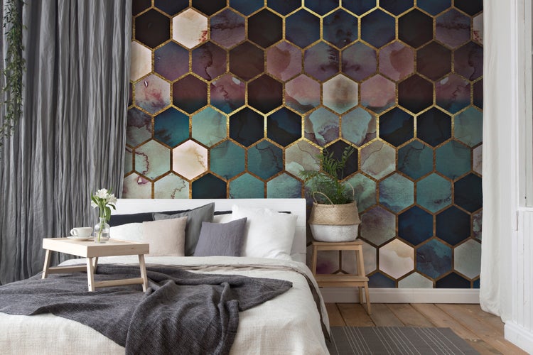 Vliestapete mit hexagonalem Wabenmuster in Aquarell-Optik hinter einem hellen Bett in einem modern eingerichteten Schlafzimmer.