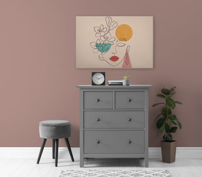 Eine Kommode mit vier Schubladen steht vor einer Wand mit einem abstrakten Wandbild, einem Hocker und einer Zimmerpflanze im Innenraum.