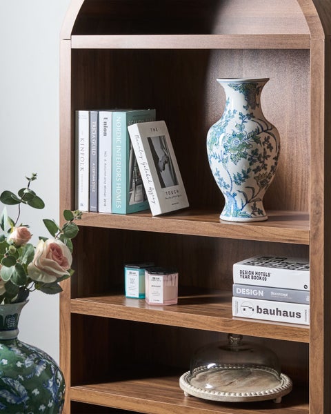 Holzregal mit Dekorationsgegenständen wie Vasen, Büchern und Duftkerzen