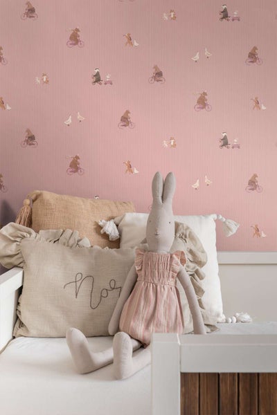 Kindertapete mit Tiermotiven und feiner Streifenstruktur im Kinderzimmer mit weichem Plüschhasen und Dekokissen auf weißem Kinderbett.