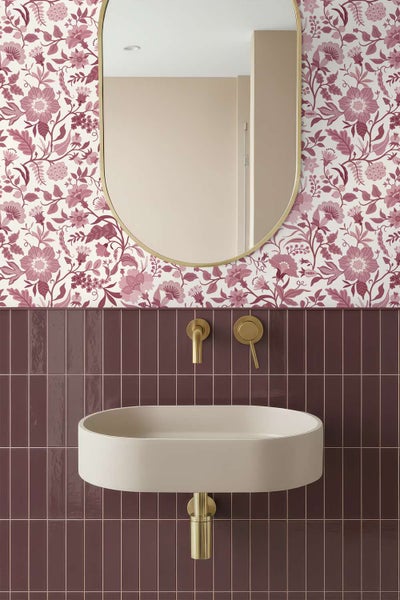 Modernes Badezimmer mit Blumenmustertapete, rechteckigen Wandfliesen, ovalem Spiegel und hängendem Waschbecken mit Armatur in Metalloptik.
