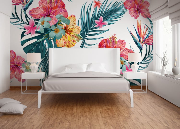 Schlafzimmer mit weißem Bett und Fototapete mit tropischen Hibiskusblüten sowie Palmenblättern.