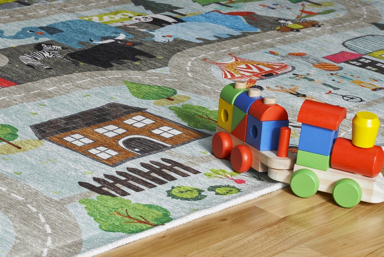 Kinderteppich mit Stadt-, Straßen- und Zoomotiven sowie einem Holzspielzeugzug auf hellem Holzboden.