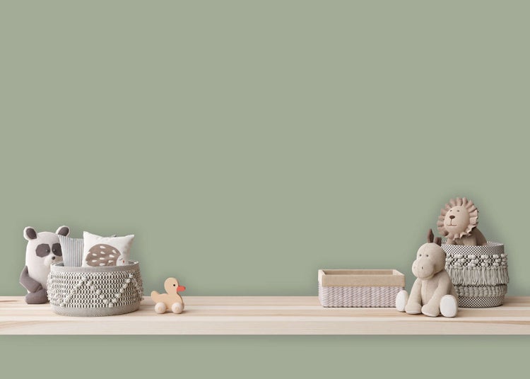 Kinderzimmer mit Wandfarbe in Salbeigrün, hellem Holzregal, geflochtenen Körben und verschiedenen Stofftieren.