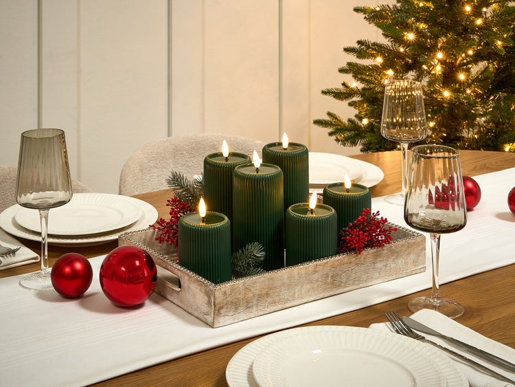 Festlich gedeckter Tisch mit LED-Kerzen, Gläsern, Tellern und Weihnachtsschmuck