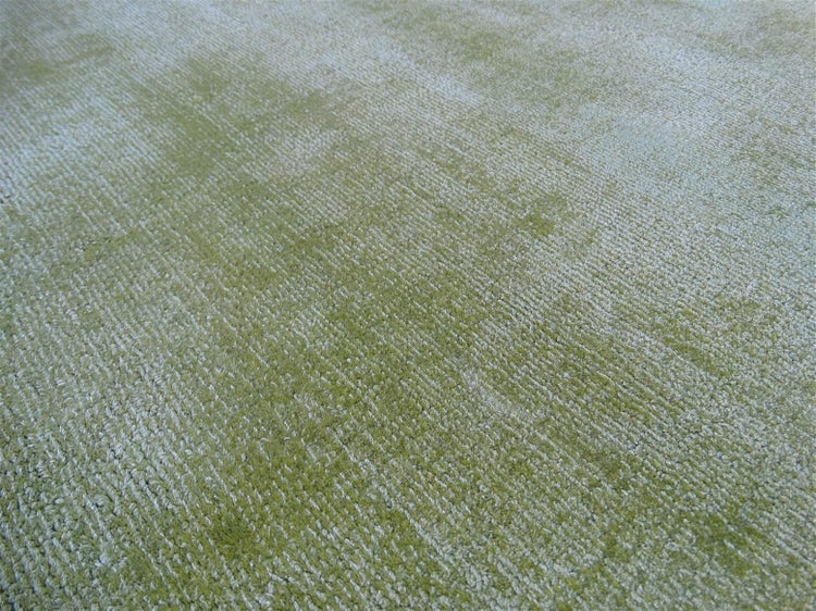Nahaufnahme eines grünen Teppichs mit gerippter Struktur und melierter Optik.