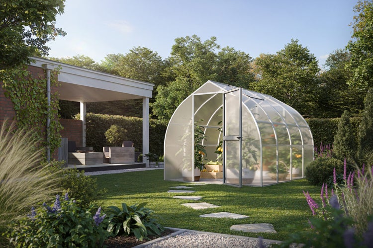Gewächshaus mit Rundbogendach aus Polycarbonat in einem gestalteten Garten mit Rasen, Steinpfad und Terrassenbereich.