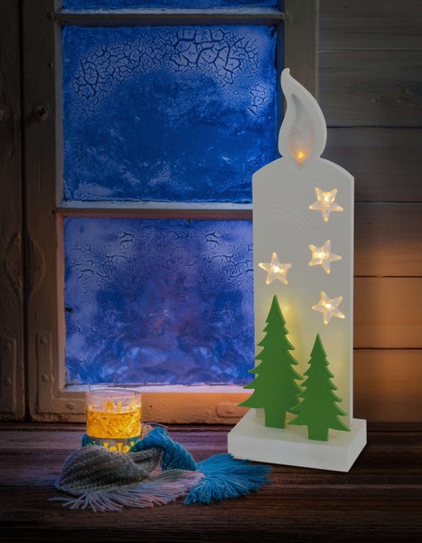 Dekorative LED Kerze mit Sternen und Tannenbäumen vor einem frostigen Fenster