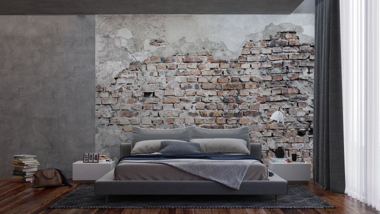Schlafzimmer mit Bett vor einer Backsteinmauer