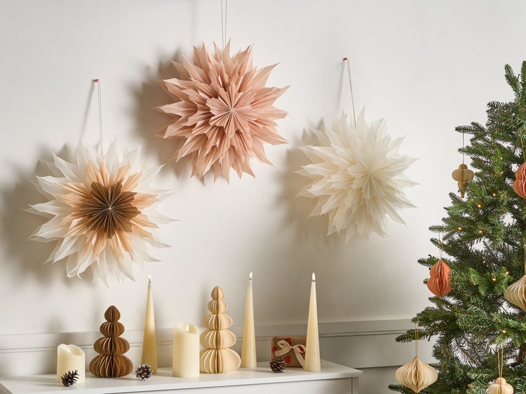 Dekorative Szene mit Papiersternen, Kerzen und Weihnachtsbaum für festliche Atmosphäre