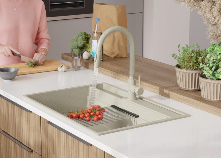 Küchenszene mit Spüle, Armatur, Gemüse und einer Person, die kocht