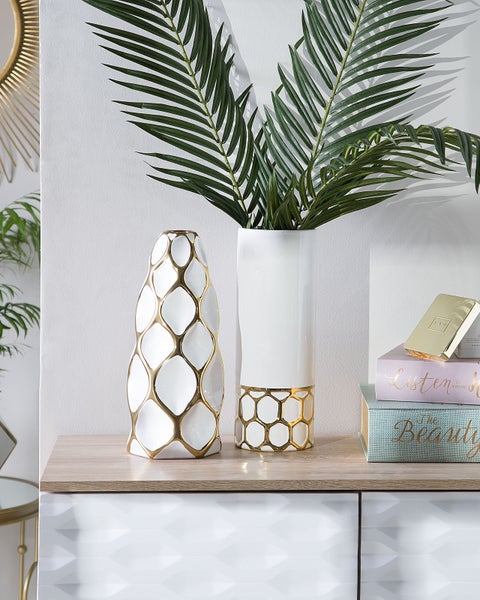 Dekorative weiße und goldene Vasen mit Pflanzen auf einem Sideboard