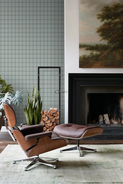 Wohnzimmer mit Sessel, Ottomane, Kamin und Dekorationen für eine gemütliche Atmosphäre.