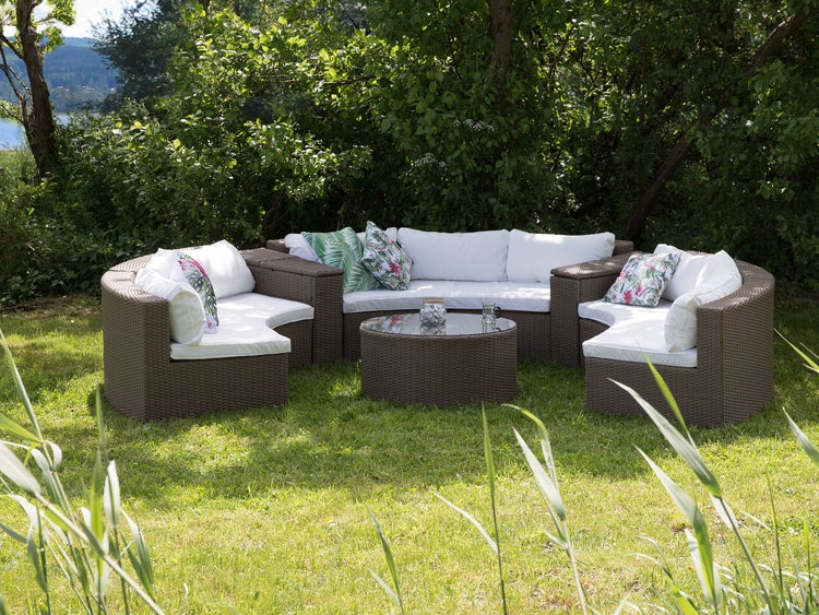 Gartenlounge-Set aus Rattan mit Sofa, Sesseln, Kissen und Tisch im Garten