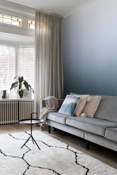 Wohnzimmer mit Sofa, Teppich und Vorhängen