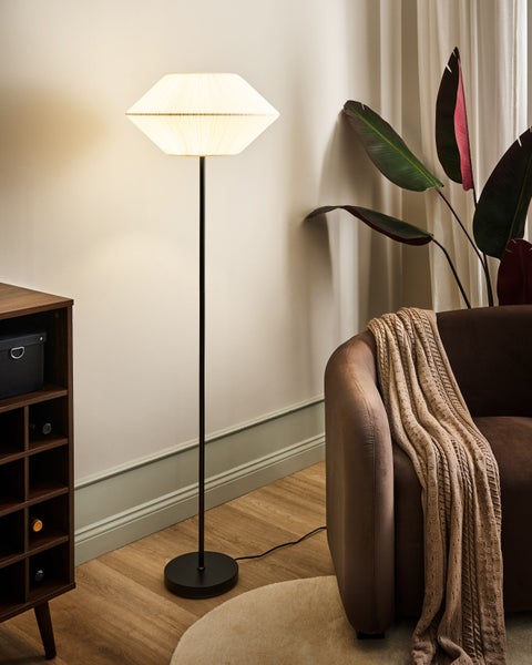 Stehleuchte im Wohnzimmer neben einem Sessel und einem Regal.