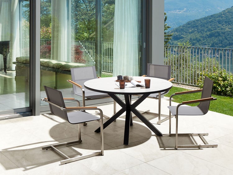 Terrasse mit rundem Tisch und Stühlen im Freien.