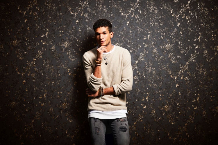 Mann vor gemusterter Tapete mit Ornamenten