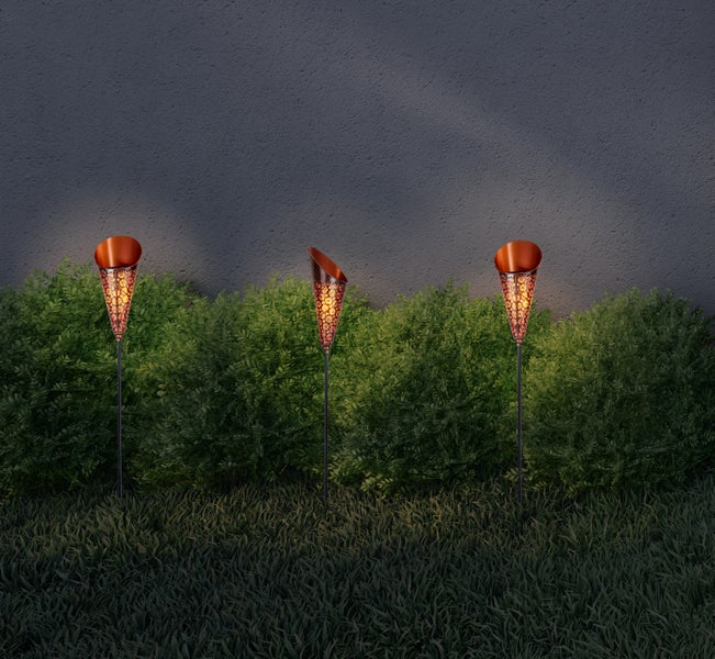 Drei dekorative Gartenfackeln beleuchten einen Gartenbereich.