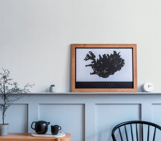 Dekorativer Wohnraum mit Islandkarte im Rahmen, Teekanne, Tasse und Zimmerpflanzen