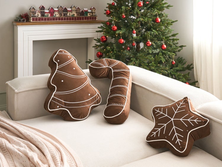 Dekorative Weihnachtskissen in Form von Lebkuchen auf Sofa vor Weihnachtsbaum