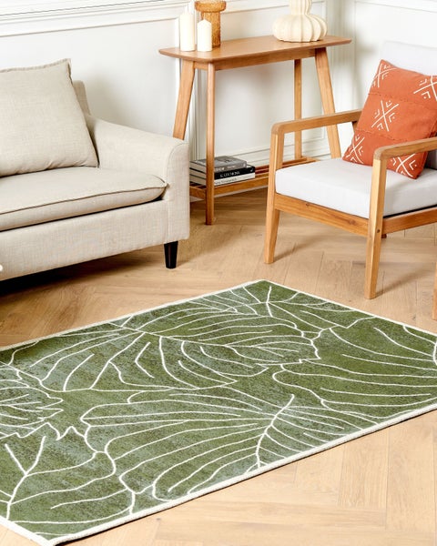 Wohnszene mit grünem Teppich mit Blattmuster, Sofa und Sessel