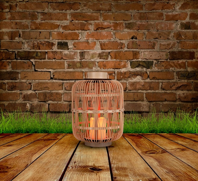 Dekorative Laterne mit Kerze vor einer Backsteinmauer und Holzboden