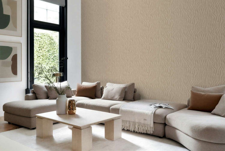 Wohnzimmer mit beigefarbener Tapete mit Wellenmuster, großem Sofa und hellem Holztisch in einem modernen, lichtdurchfluteten Wohnbereich.