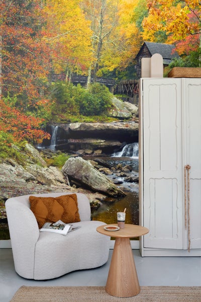 Szene mit Sessel, Tisch und Fototapete mit Herbstlandschaft