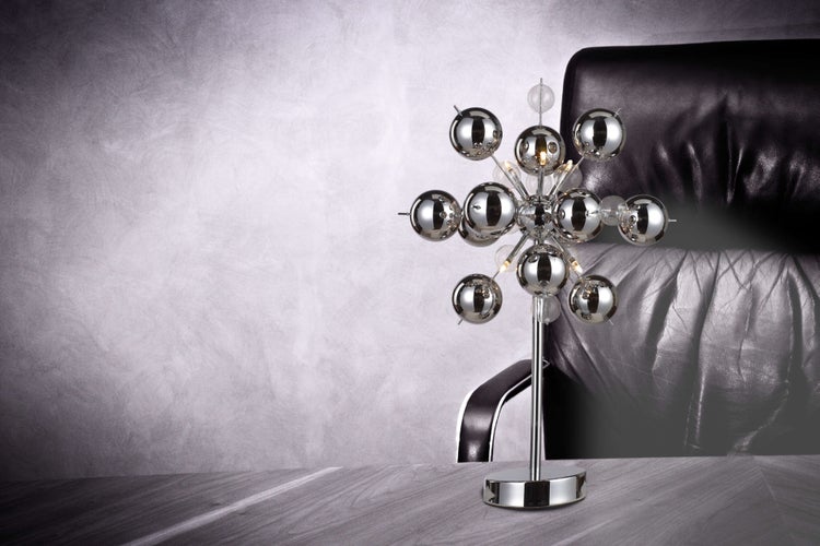 Dekorative Tischleuchte mit kugelförmigen Elementen vor einem Ledersessel