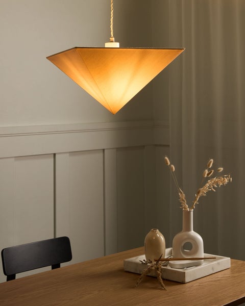 Innenaufnahme mit einer pyramidenförmigen Hängeleuchte über einem Holztisch mit dekorativen Vasen