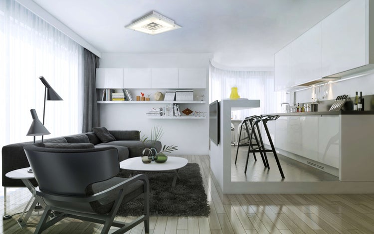 Helles Wohnzimmer mit Sofa, Stühlen, Teppich und Küchenbereich