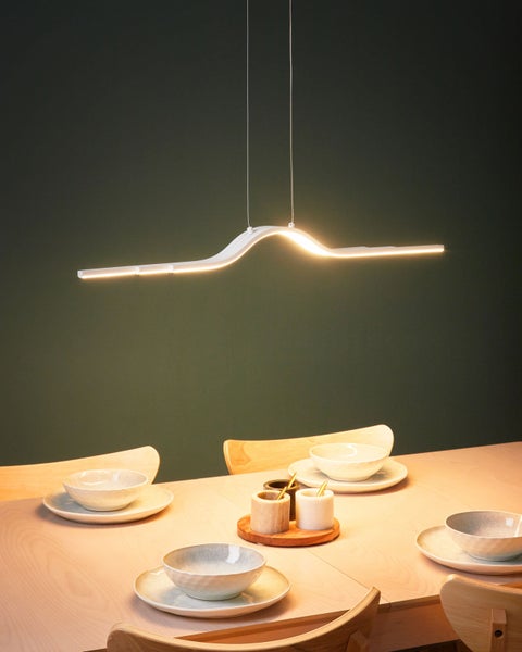 Moderne LED-Pendelleuchte über einem Esstisch mit Geschirr