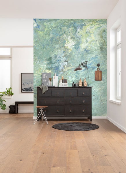 Wohnraum mit gemusterter Tapete, Kommode, Hocker und Dekoration