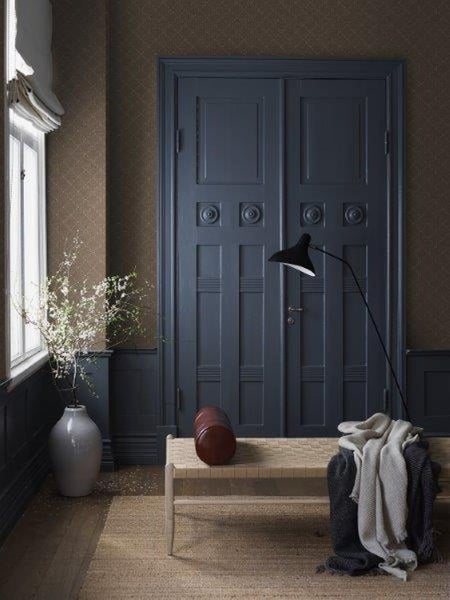 Eingangsbereich mit Doppeltür, Bank, Stehlampe und dekorativen Elementen für ein stilvolles Wohnambiente