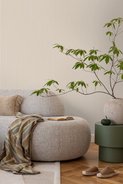 Wohnzimmer mit Sofa, Buch, Pflanze und gestreifter Tapete für ein gemütliches Ambiente.