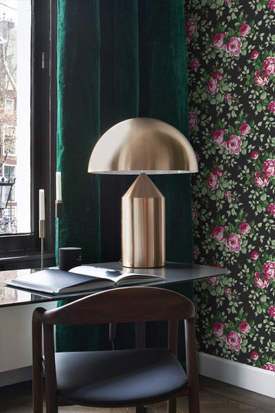 Dekoratives Zimmer mit Schreibtisch, Lampe, Stuhl, Vorhängen und floraler Tapete