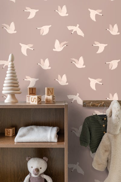 Szene eines Kinderzimmers mit Möbeln und Dekoration vor einer Tapete mit Schwanenmuster.