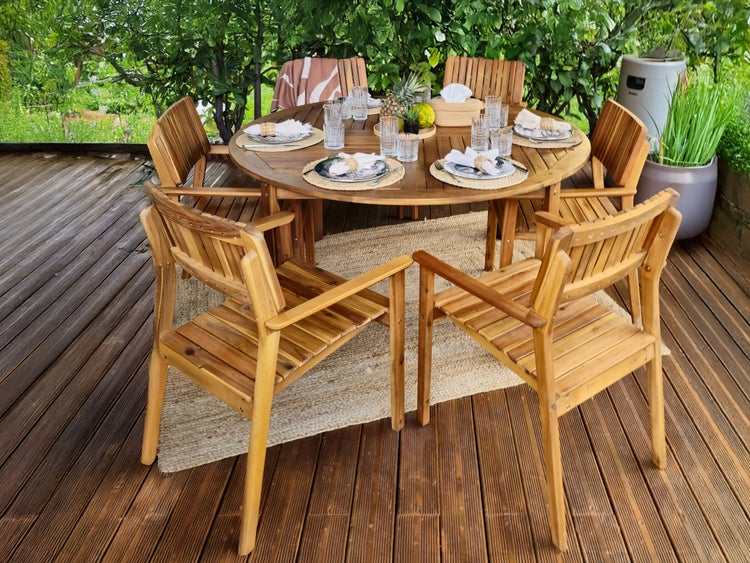 Gartenszene mit rundem Holztisch, Stühlen und Tischdekoration auf einer Terrasse