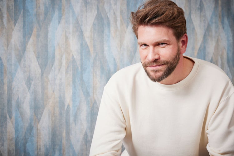 Dekorative Tapete mit Blättermuster in einem Wohnraum mit Mobiliar und Beleuchtung. D'eco Logo: PVC-frei, Wasserbasierte und lösungsmittelfreie Rezepturen, Phthalat-frei.