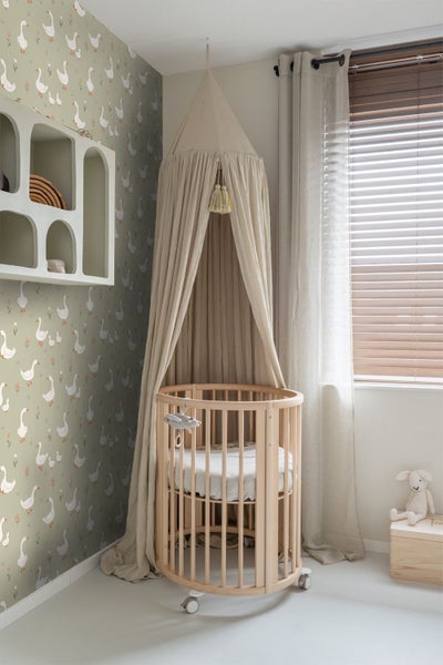 Zimmer mit rundem Kinderbett unter Baldachin vor Tapete mit Gänsemuster