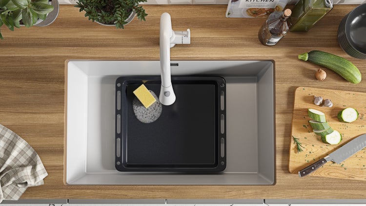 Spüle mit Backblech, Spülmittel und Spülschwamm auf einer Arbeitsplatte