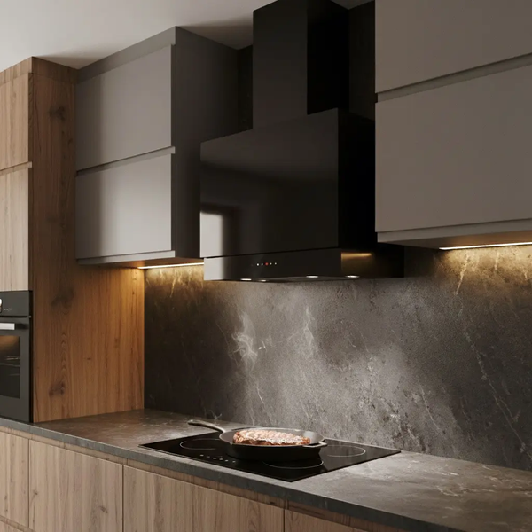 Schwarze Wand-Dunstabzugshaube in einer modernen Küche über einem Kochfeld mit Pfanne und Steinrückwand.