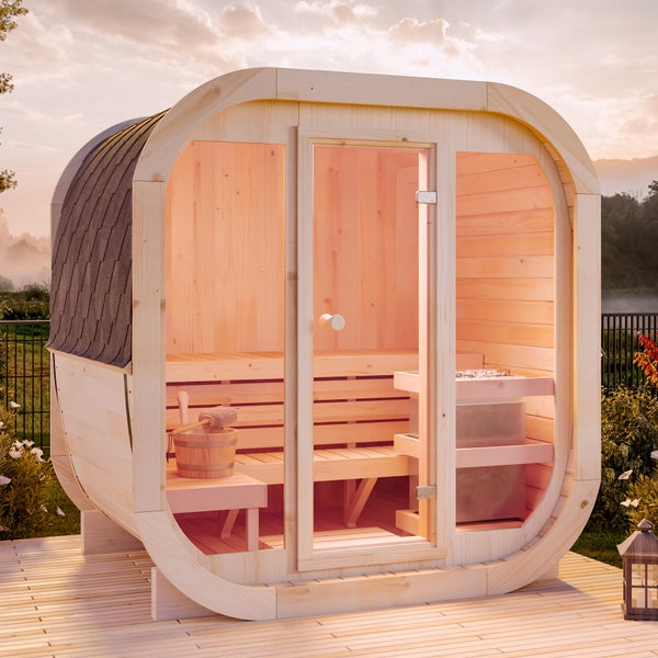 Fasssauna aus hellem Holz mit Glasfront, Saunaofen, Holzbänken und Zubehör auf einer Terrasse im Garten.