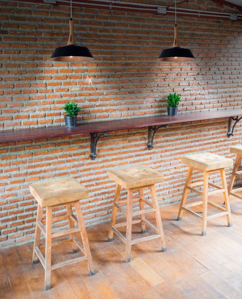 Innenraum mit Barhockern, Holztisch, Backsteinmauer und Hängelampen
