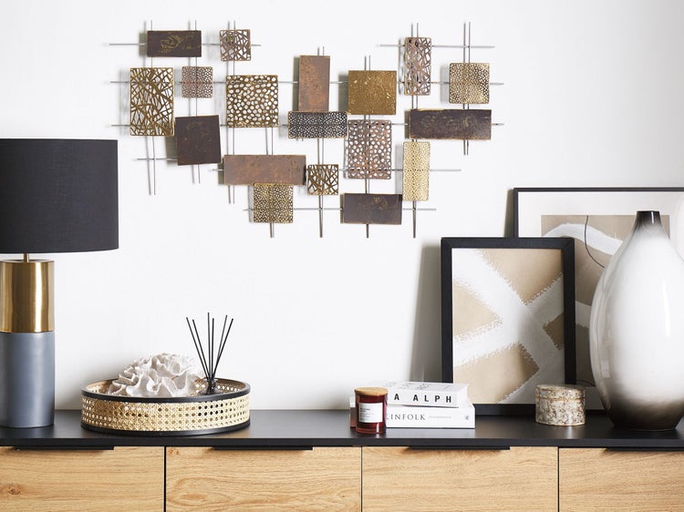 Wohnzimmerdekoration mit Wanddekoration aus Metall, Tischlampe und Kommode.