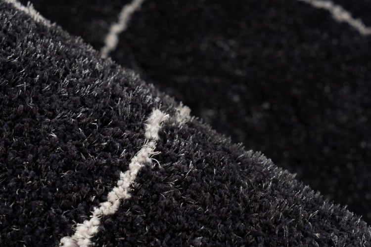 Nahaufnahme eines dunkelgrauen Hochflor-Teppichs mit hellen Linien.