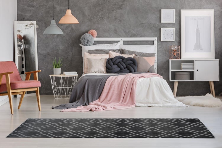 Nahaufnahme eines anthrazitfarbenen Teppichs mit geometrischem Quadratmuster und weicher, dichter Oberfläche.